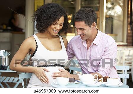 Stock Photo - Expectant couple sitting outside café. Fotosearch