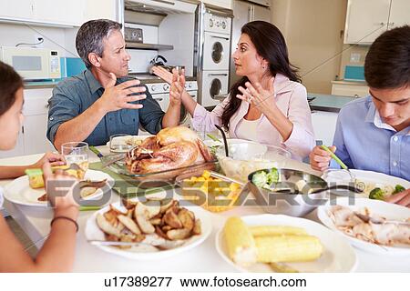 Stock Photo - Family Having Argument Sitting Around Table Eating Meal. Fotosearch