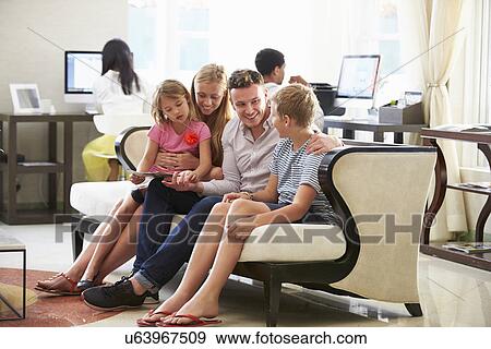 Family In Hotel Lobby Looking At Digital Tablet View Large Photo Image Stock Photo - Family In Hotel Lobby Looking At Digital Tablet. Fotosearch