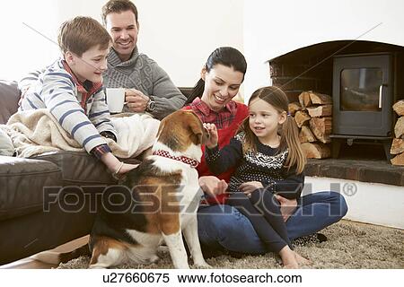Stock Photography - Family Relaxing Indoors And Stroking Pet Dog. Fotosearch