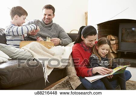 Family Relaxing Indoors Playing Chess And Reading Book View Large Photo Image Stock Photo - Family Relaxing Indoors Playing Chess And Reading Book. Fotosearch