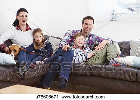 Stock Image - Family Relaxing Indoors Watching Television Together. Fotosearch