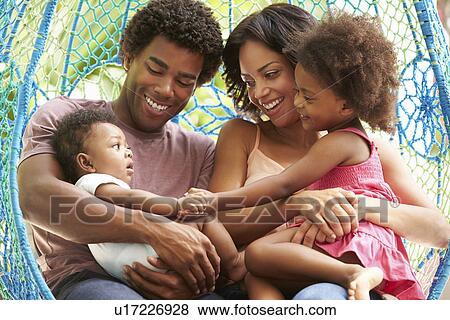 Stock Photo - Family Relaxing On Outdoor Garden Swing Seat. Fotosearch
