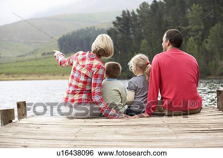 Stock Photograph - Family sitting on a jetty. Fotosearch