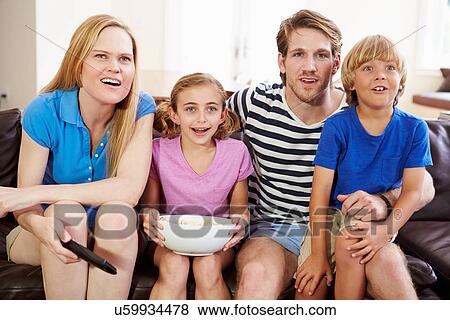 Stock Photo - Family Sitting On Sofa Watching Soccer Together. Fotosearch