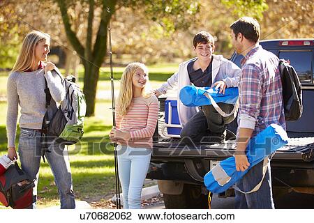 Stock Image - Family Unpacking Pick Up Truck On Camping Holiday. Fotosearch