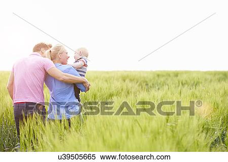 Stock Photography - Family Walking In Field Carrying Young Baby Son. Fotosearch