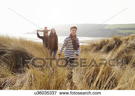 Stock Photo - Family Walking Through Sand Dunes On Winter Beach. Fotosearch