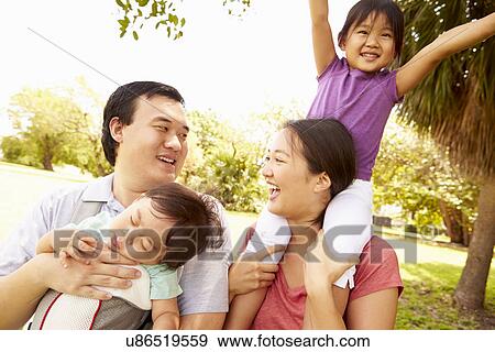 Stock Photo - Family With Baby In Carrier Walking Through Park. Fotosearch