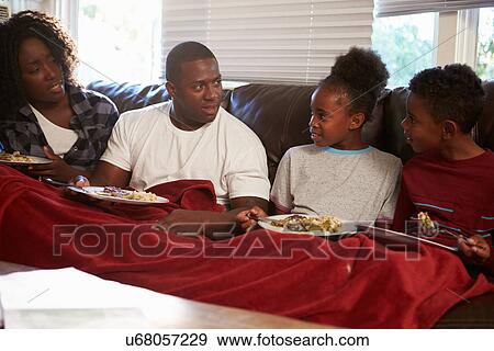Stock Photo - Family With Poor Diet Sitting On Sofa Eating Meal. Fotosearch