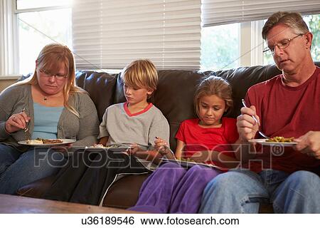 Family With Poor Diet Sitting On Sofa Eating Meal View Large Photo Image Stock Photograph - Family With Poor Diet Sitting On Sofa Eating Meal. Fotosearch