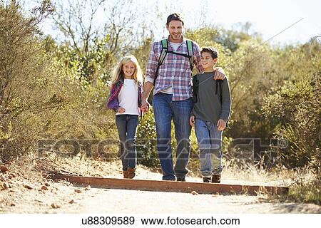Stock Photo - Father And Children Hiking In Countryside Wearing Backpacks. Fotosearch