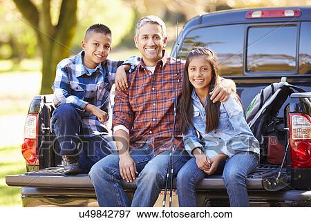 Stock Photo - Father And Children Sitting In Truck On Camping Holiday. Fotosearch