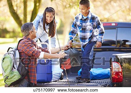 Stock Photo - Father And Children Unpacking Truck On Camping Holiday. Fotosearch