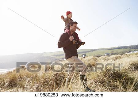 Stock Image - Father And Daughter Walking Through Dunes On Winter Beach. Fotosearch