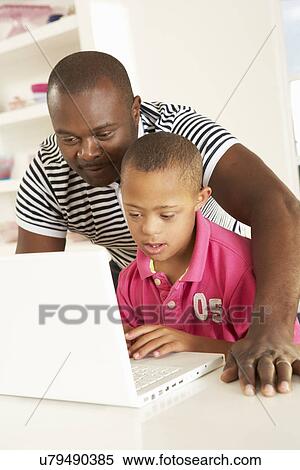 Stock Photography - Father and Downs Syndrome son with laptop. Fotosearch