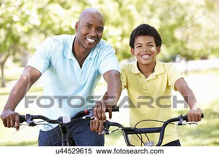 Father and son cycling in park View Large Photo Image Stock Photography - Father and son cycling in park. Fotosearch