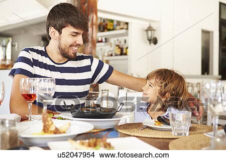 Picture - Father And Son Enjoying Meal In Restaurant. Fotosearch
