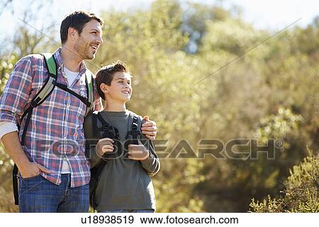 Stock Photo - Father And Son Hiking In Countryside Wearing Backpacks. Fotosearch