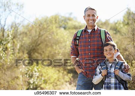 Stock Photo - Father And Son Hiking In Countryside Wearing Backpacks. Fotosearch