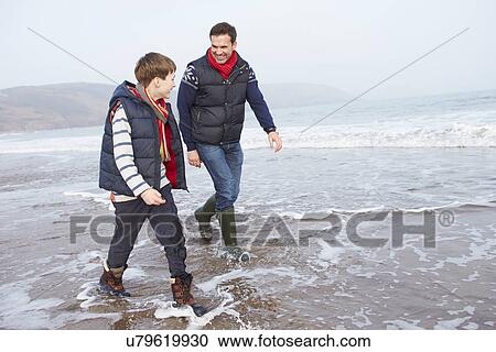 Stock Image - Father And Son Walking On Winter Beach. Fotosearch