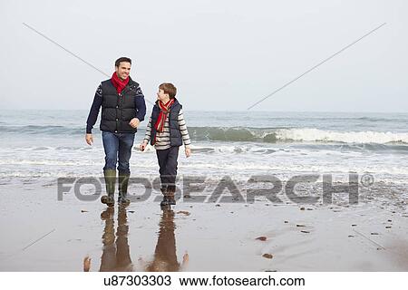 Stock Image - Father And Son Walking On Winter Beach. Fotosearch