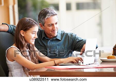 Stock Image - Father And Teenage Daughter Looking At Laptop Together. Fotosearch