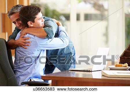 Stock Image - Father And Teenage Son Having A Hug. Fotosearch