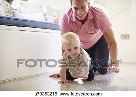 Stock Photograph - Father And Young Son Crawling Around Room Together. Fotosearch