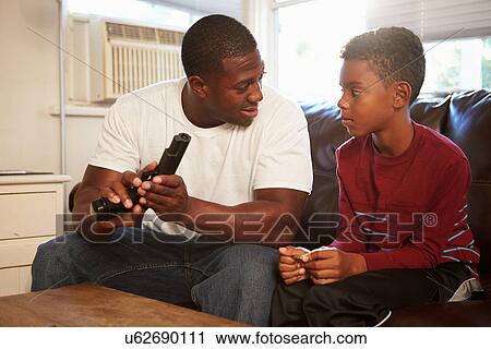 Father Checks Gun As Son Sits Next To Him On Sofa View Large Photo Image Stock Image - Father Checks Gun As Son Sits Next To Him On Sofa. Fotosearch