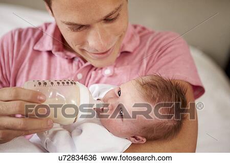 Stock Photograph - Father Giving Baby Daughter Bottle Of Milk. Fotosearch