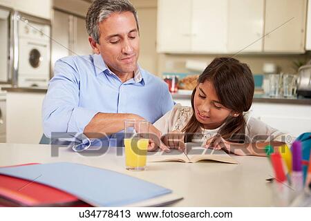 Stock Image - Father Helping Daughter With Reading Homework At Table. Fotosearch