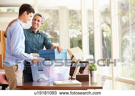 Stock Image - Father Helping Teenage Son Pack For College. Fotosearch