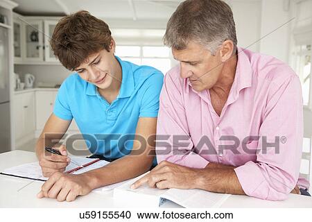 Stock Image - Father helping teenage son with homework. Fotosearch