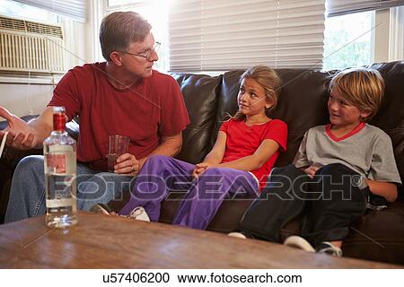Stock Image - Father Sits On Sofa With Children Smoking And Drinking. Fotosearch