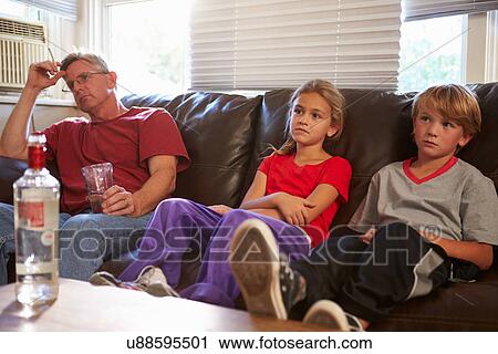 Stock Image - Father Sits On Sofa With Children Smoking And Drinking. Fotosearch
