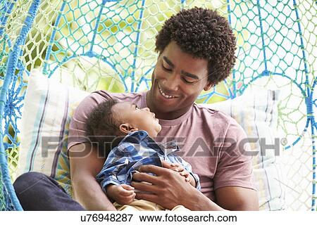 Stock Photo - Father With Baby Son Relaxing On Outdoor Garden Swing Seat. Fotosearch