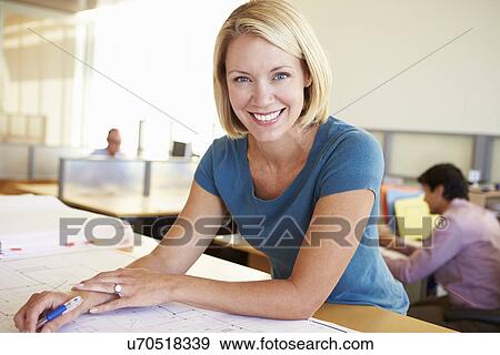 Stock Photo - Female Architect Studying Plans In Office. Fotosearch