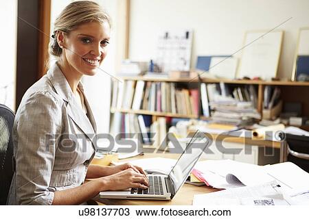 Stock Image - Female Architect Working At Desk On Laptop. Fotosearch