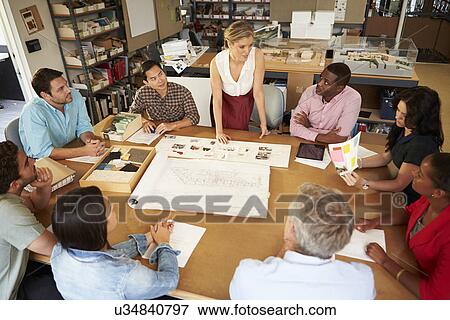 Female Boss Leading Meeting Of Architects Sitting At Table View Large Photo Image Stock Photo - Female Boss Leading Meeting Of Architects Sitting At Table. Fotosearch