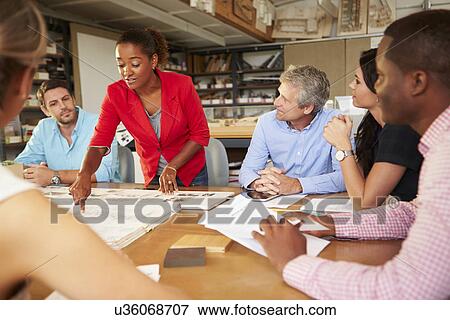 Stock Photo - Female Boss Leading Meeting Of Architects Sitting At Table. Fotosearch
