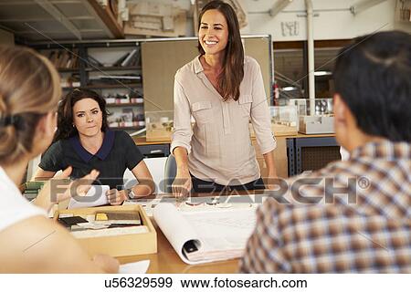Stock Photo - Female Boss Leading Meeting Of Architects Sitting At Table. Fotosearch