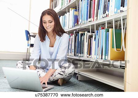 Stock Image - Female College Student Studying In Library With Laptop. Fotosearch