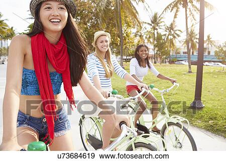 Stock Photo - Female Friends Having Fun On Bicycle Ride. Fotosearch