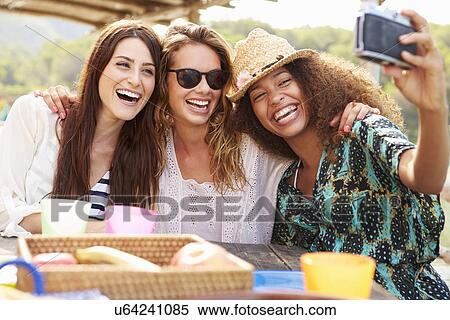 Stock Photography - Female Friends Taking Selfie During Lunch Outdoors. Fotosearch
