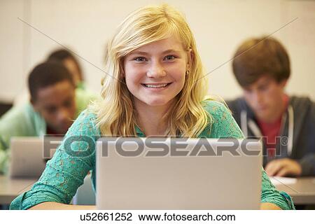 Stock Image - Female High School Student At Desk In Class Using Laptop. Fotosearch