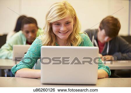 Stock Photograph - Female High School Student At Desk In Class Using Laptop. Fotosearch