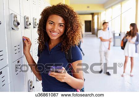 Stock Photo - Female High School Student By Lockers Using Mobile Phone. Fotosearch