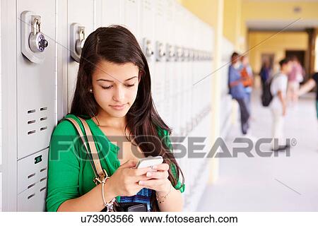 Stock Photograph - Female High School Student By Lockers Using Mobile Phone. Fotosearch