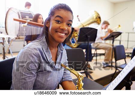 Stock Photo - Female Pupil Playing Saxophone In High School Orchestra. Fotosearch